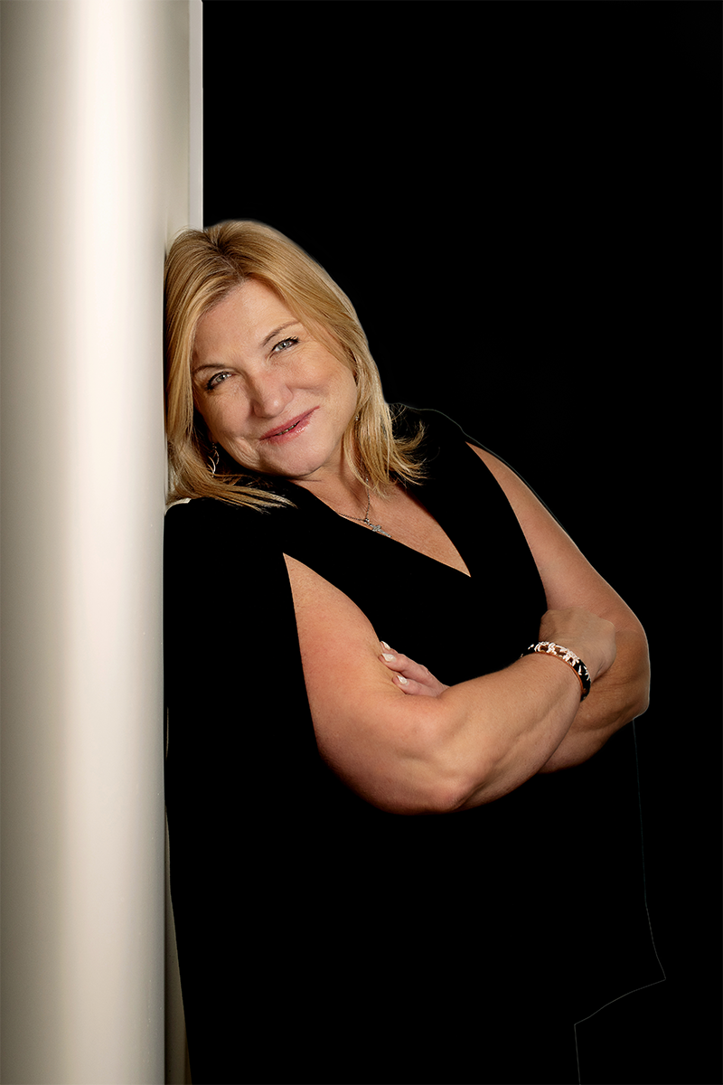 A woman leaning against a pole with her arms crossed.